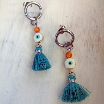 ohrstecker rund aus Edelstahl mit orangenen Achat und einer blauen Auge perle und zum abschluß einer quaste in petrolfarbe